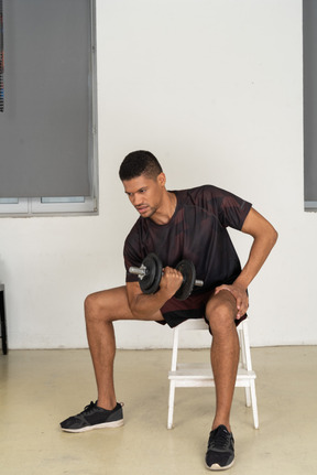 Young man in sports clothes lifting weigths