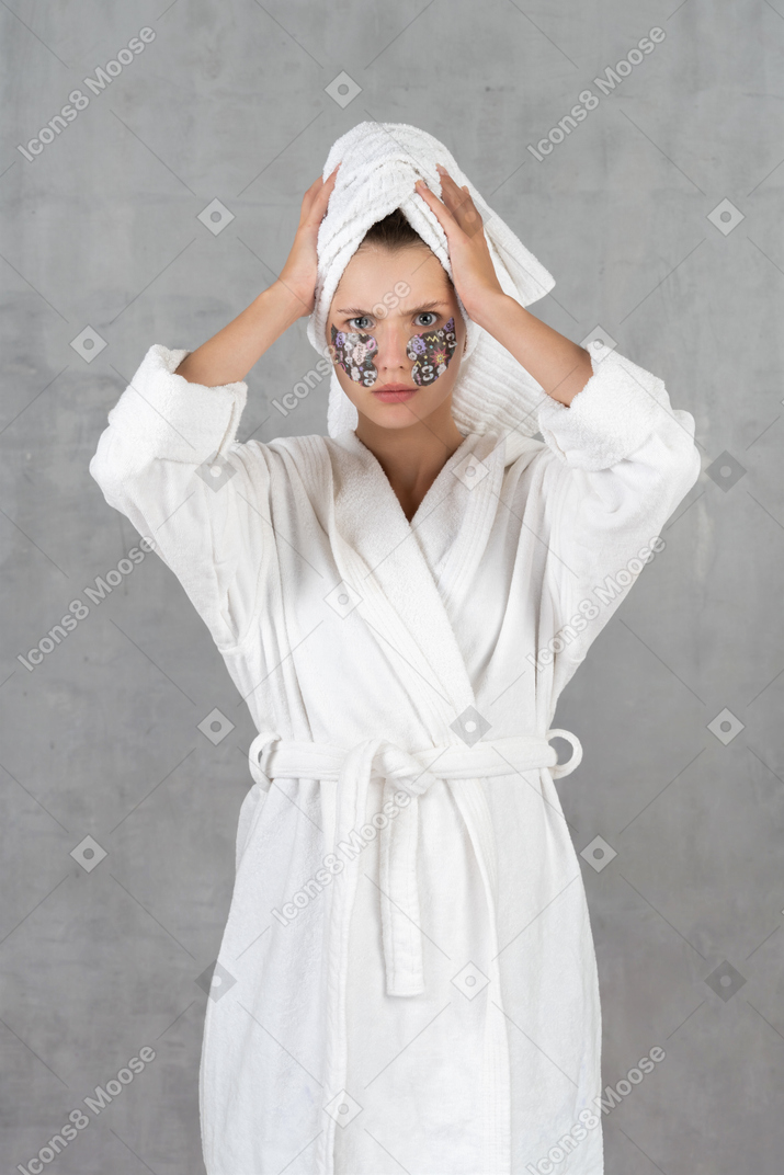 Angry-looking woman in bathrobe holding hair towel