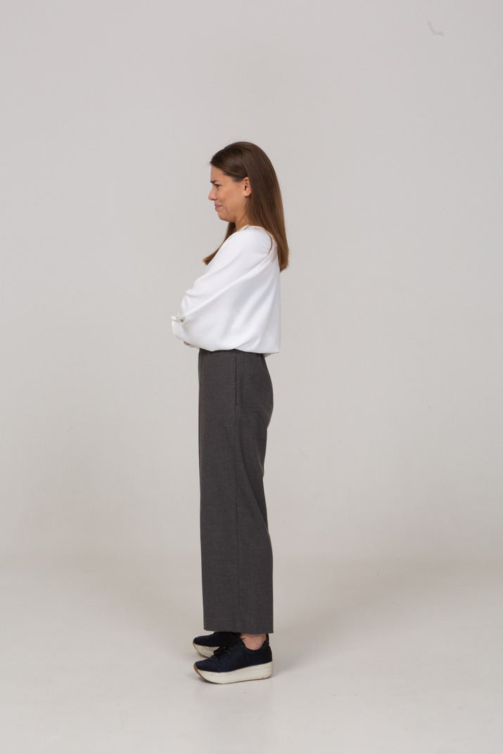 Side view of a displeased young lady in office clothing crossing arms
