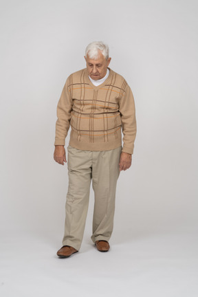 Front view of an old man in casual clothes looking down