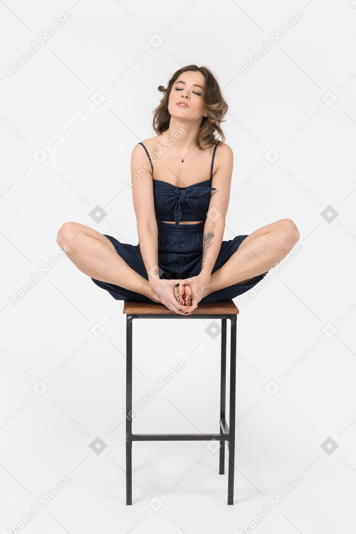 Carefree woman sitting on bar chair in lotus position