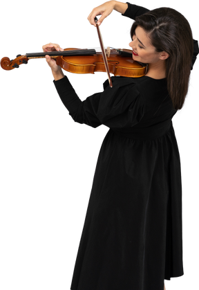 Close-up de uma jovem alegre de vestido preto tocando violino