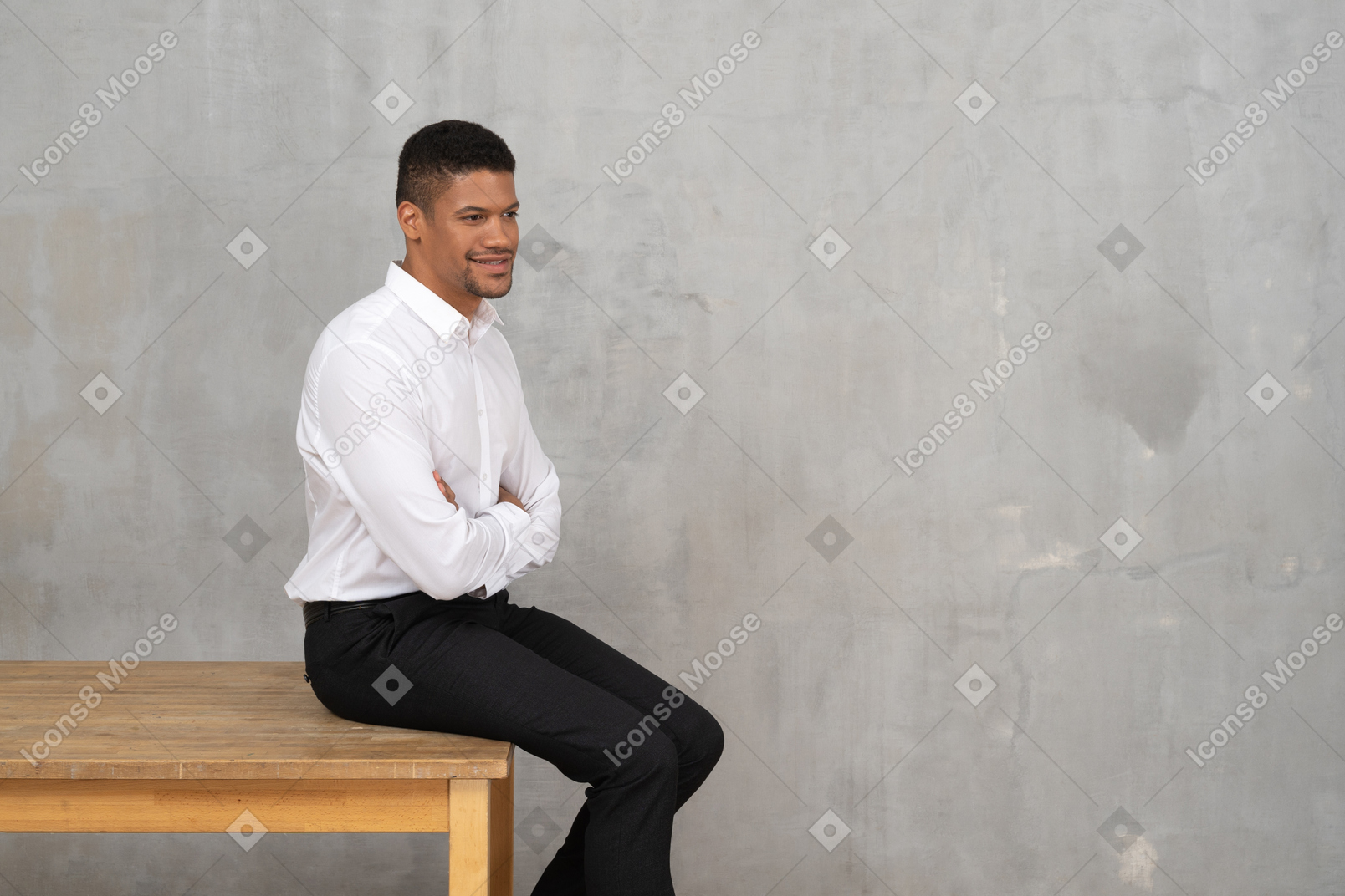 Smiling man in office clothes sitting on a table with his arms crossed