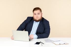 Beschäftigt aussehende junge übergewichtige sitzen am schreibtisch