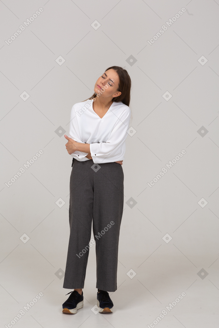 Vista frontal de uma jovem com roupa de escritório e dor de estômago, curvando-se