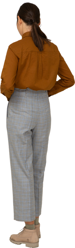 Vista posteriore di tre quarti di una giovane donna asiatica in calzoni e camicetta che tocca lo stomaco