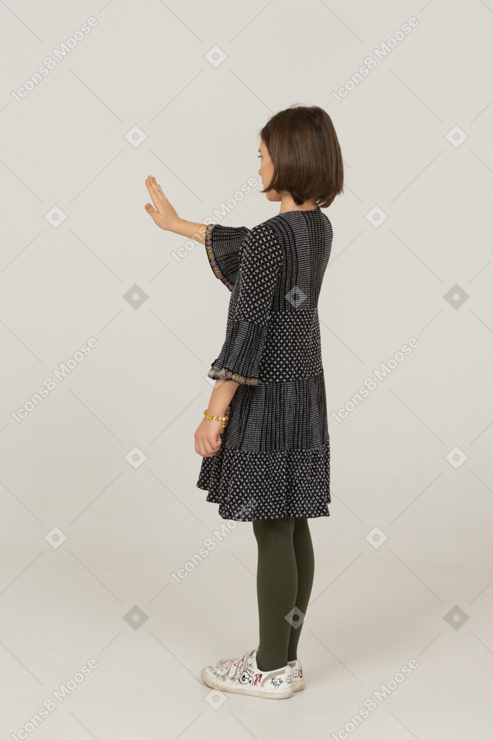 Three-quarter back view of a little girl in dress outstretching her hand