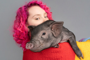 Pink haired female holding a little piglet