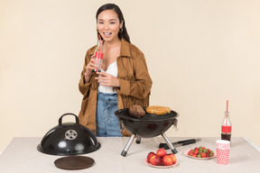 Rire jeune femme asiatique tenant coke et faire un barbecue