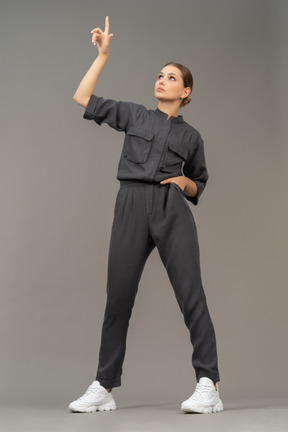 Front view of a young woman in a jumpsuit outstretching her arm