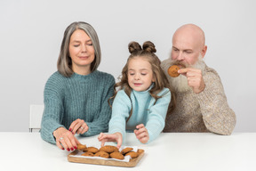 Бабушка и дедушка и ребенок девочка держит печенье