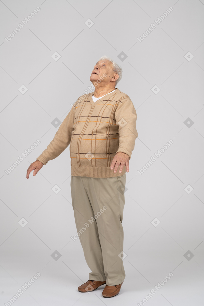 Vorderansicht eines beeindruckten alten mannes, der auf zehenspitzen steht und nach oben schaut