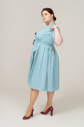 Vista laterale di una donna in abito blu in posa con le mani sulle spalle