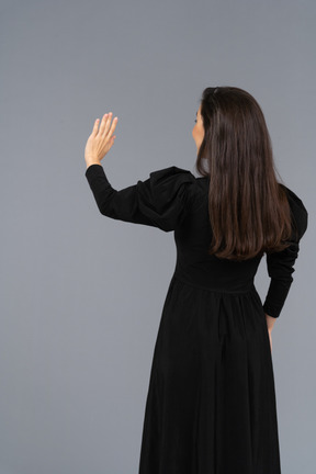 后面的观点的一位年轻的女士穿着黑裙子举起她的手