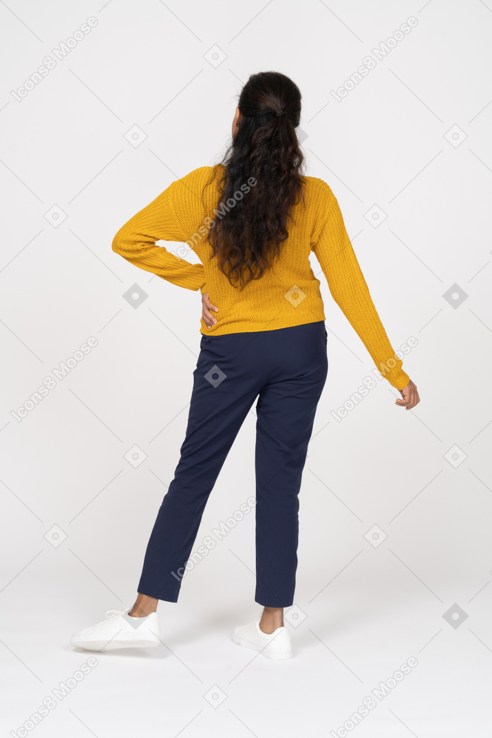 一个女孩在休闲摆姿势用手放在臀部的后视图