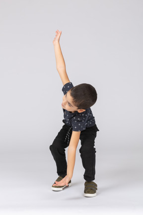 Front view of a cute boy touching floor with hand