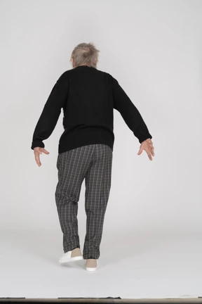 Elderly man walking away with arms extended backwards