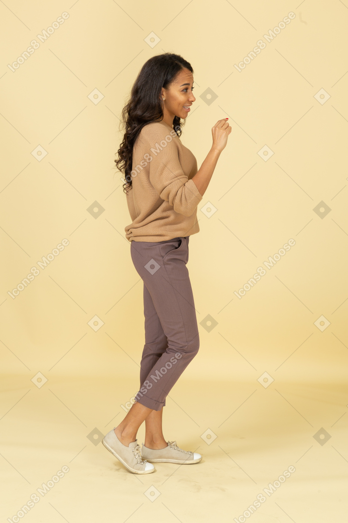 Vista lateral de una mujer joven de piel oscura que muestra un tamaño pequeño de algo