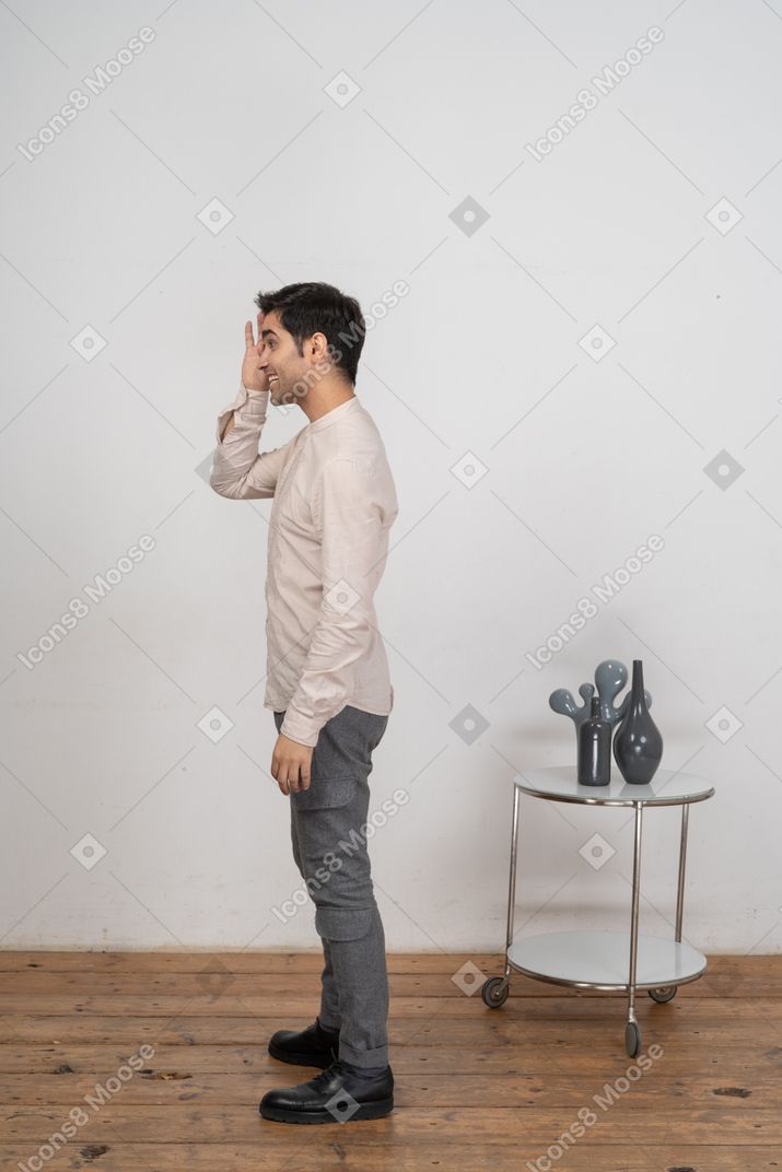 Vista lateral de un hombre en ropa casual mirando a través de los dedos
