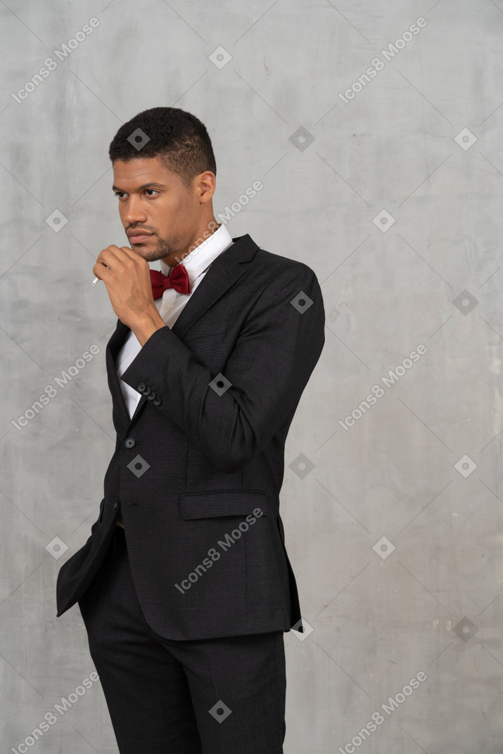 Вид спереди на мужчину в черном костюме, держащего сигарету