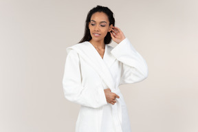 Black woman in white bathrobe going about her morning routine