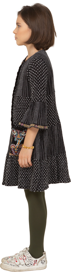 Vista lateral de uma menina intrigada com um vestido tricotando sobrancelhas