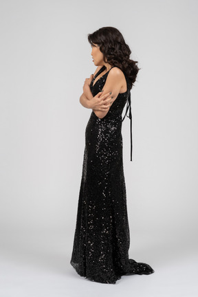 Woman in black evening dress standing in profile to camera