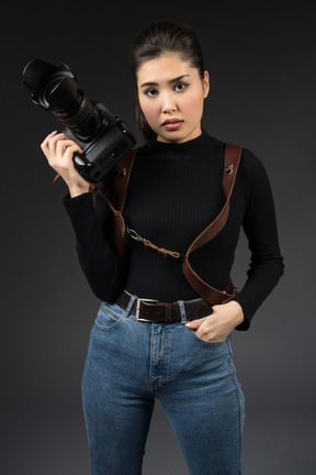 Beautiful young woman posing with camera in hand