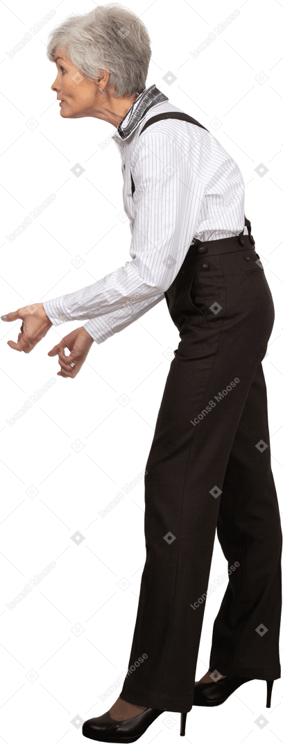 Vista lateral de una anciana haciendo muecas en ropa de oficina apretando los puños