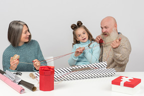 Großeltern und enkelin, die threads beim einwickeln von geschenken halten