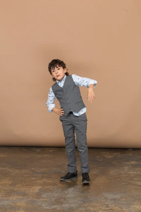 Front view of a boy in grey suit standing with hands on hips