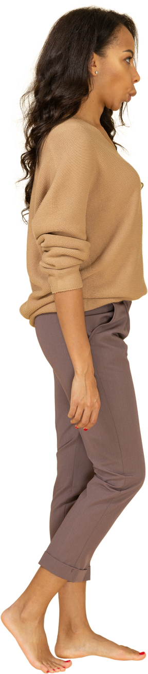 Vista lateral de una mujer joven sorprendida haciendo muecas en ropa casual