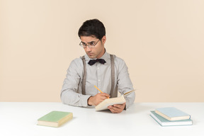 Profesor sentado a la mesa y leyendo libros