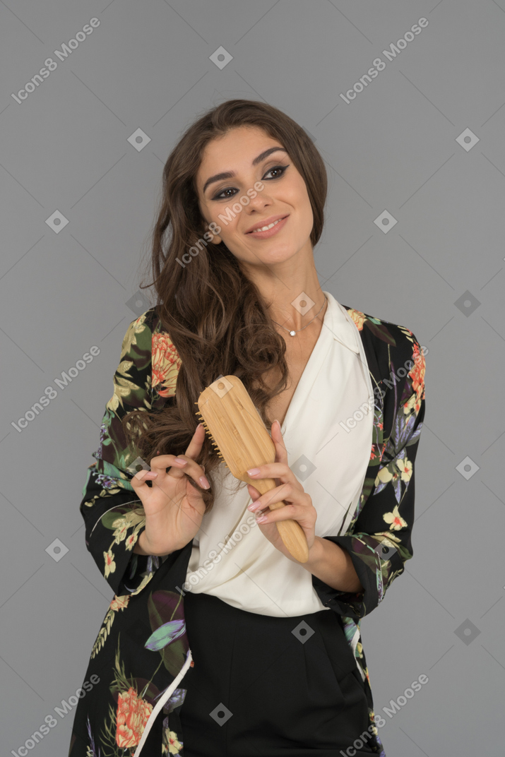 Mulher árabe sorridente, penteando o cabelo longo cacheado
