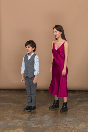 Side view of a young woman in red dress and boy