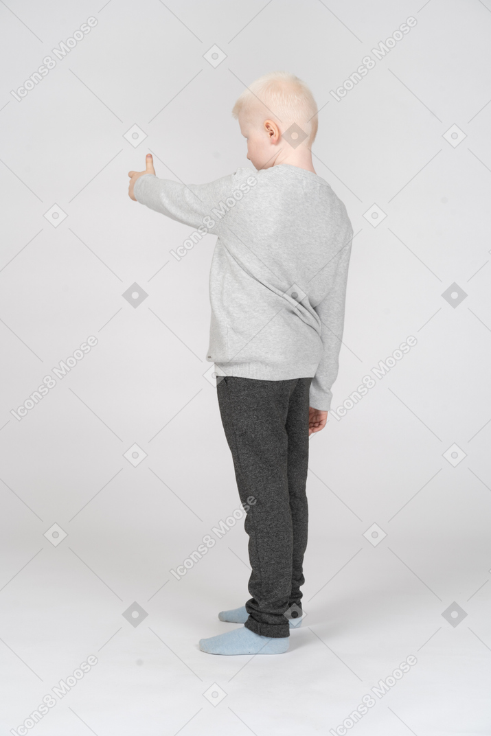 Little boy in casual clothes pointing at something