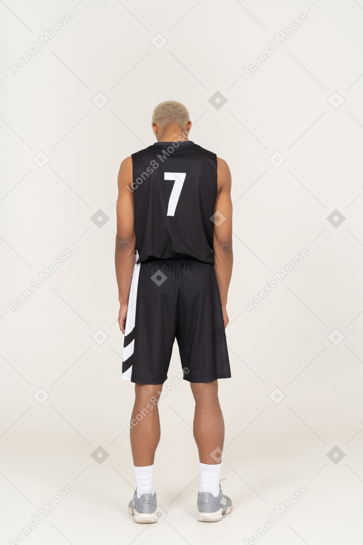 Vista traseira de um jovem jogador de basquete, parado e olhando para baixo