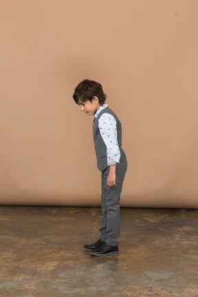 Side view of a cute boy in grey suit looking down