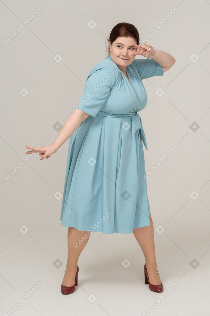 V記号を示す青いドレスを着た女性の正面図