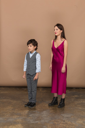 Femme en robe rouge et petit garçon debout de profil