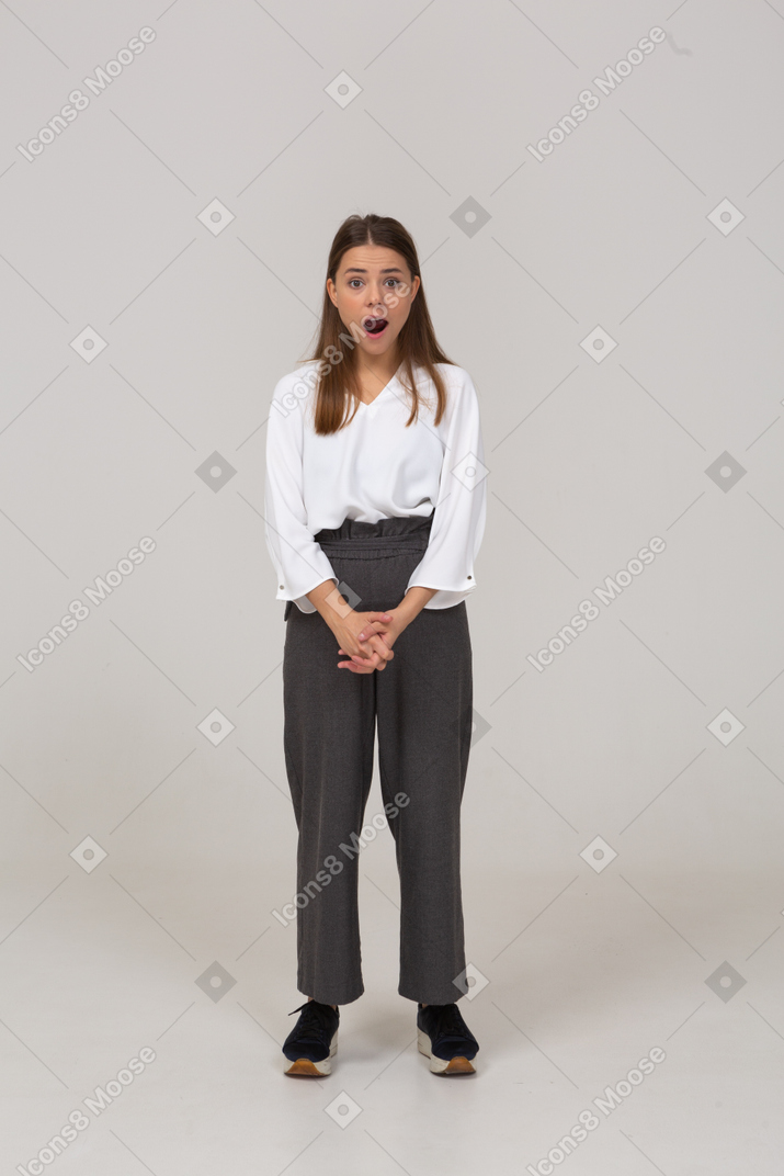 Front view of a shocked young lady in office clothing holding hands together