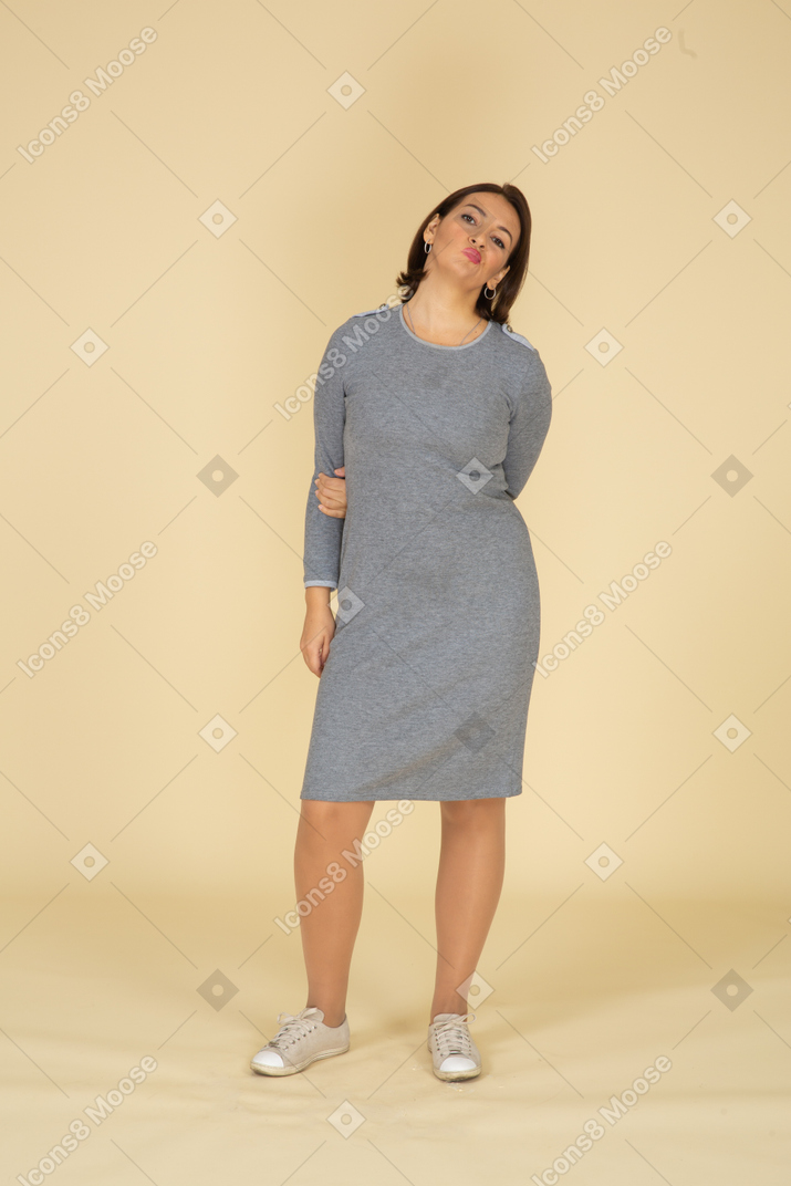 Вид спереди женщины в сером платье корчит рожи