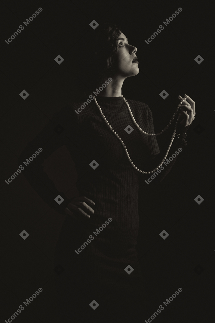 Woman with long beads standing in the dark