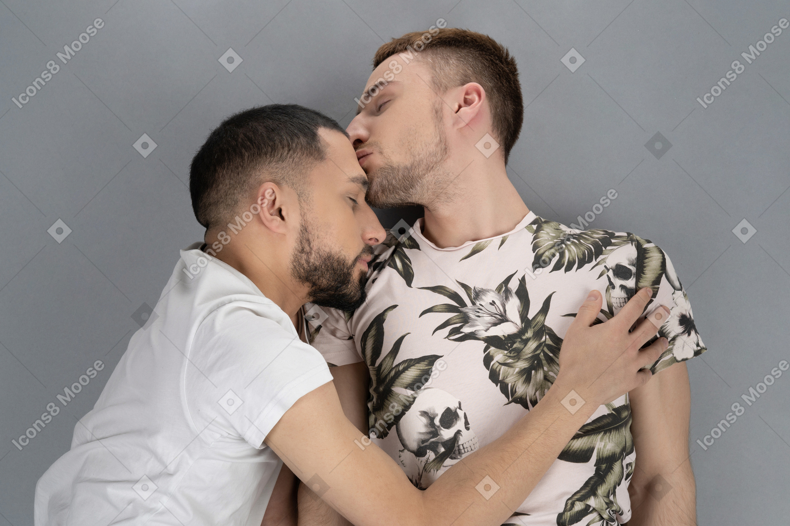 Flat lay of two young caucasian men lying on the floor hugging and kissing lightly