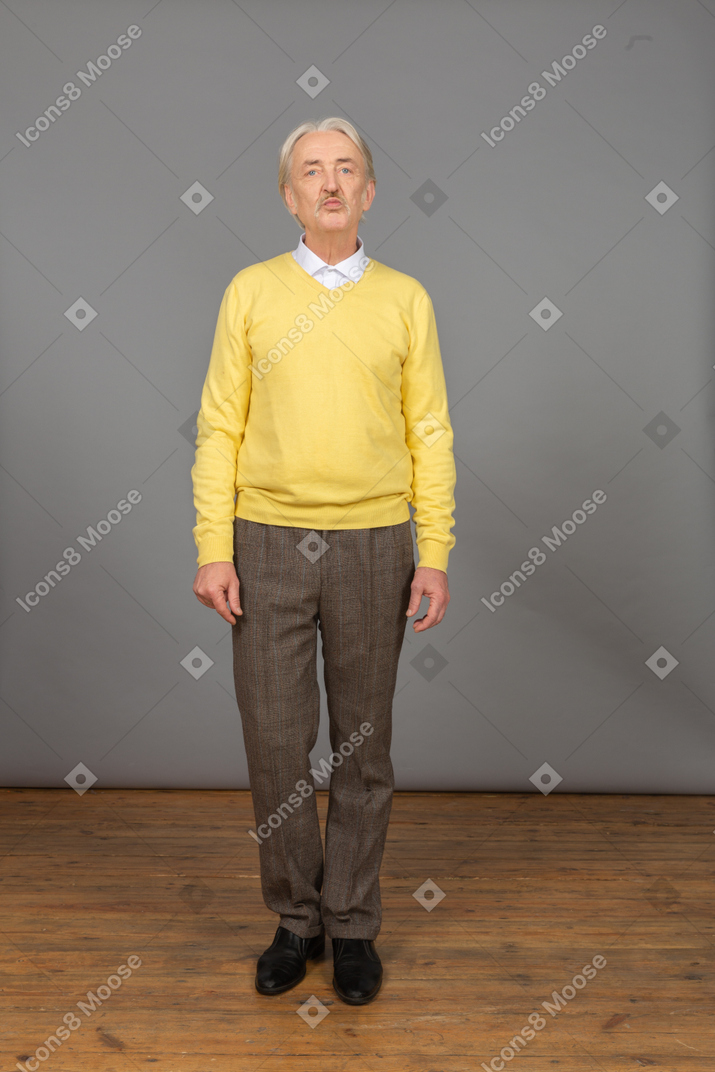 一个悲惨的老人穿着黄色套头衫，看着相机的前视图