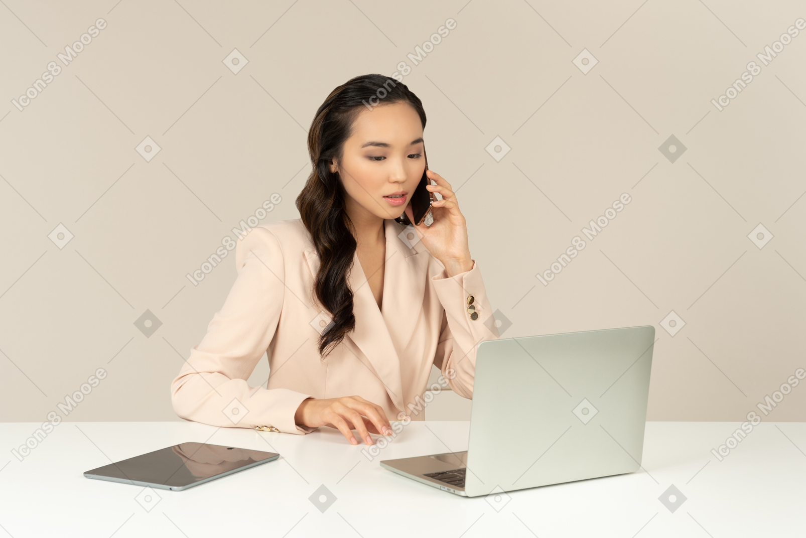 Азиатский женский офисный работник разговаривает по телефону и работает на ноутбуке