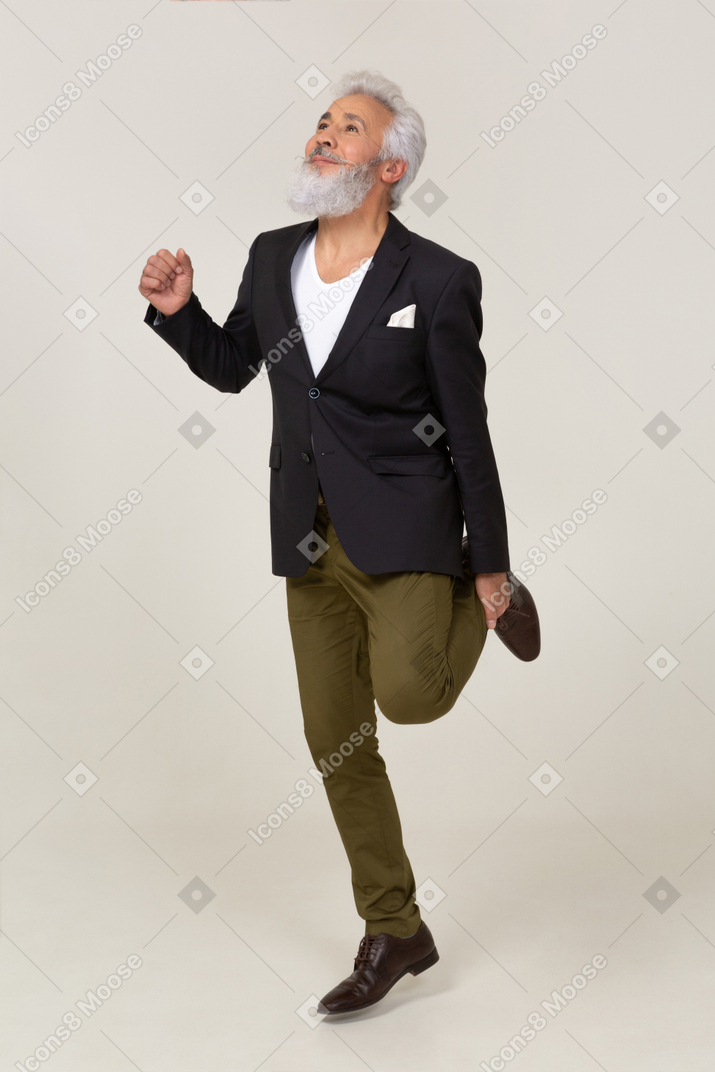 Веселый мужчина в куртке стоит на одной ноге