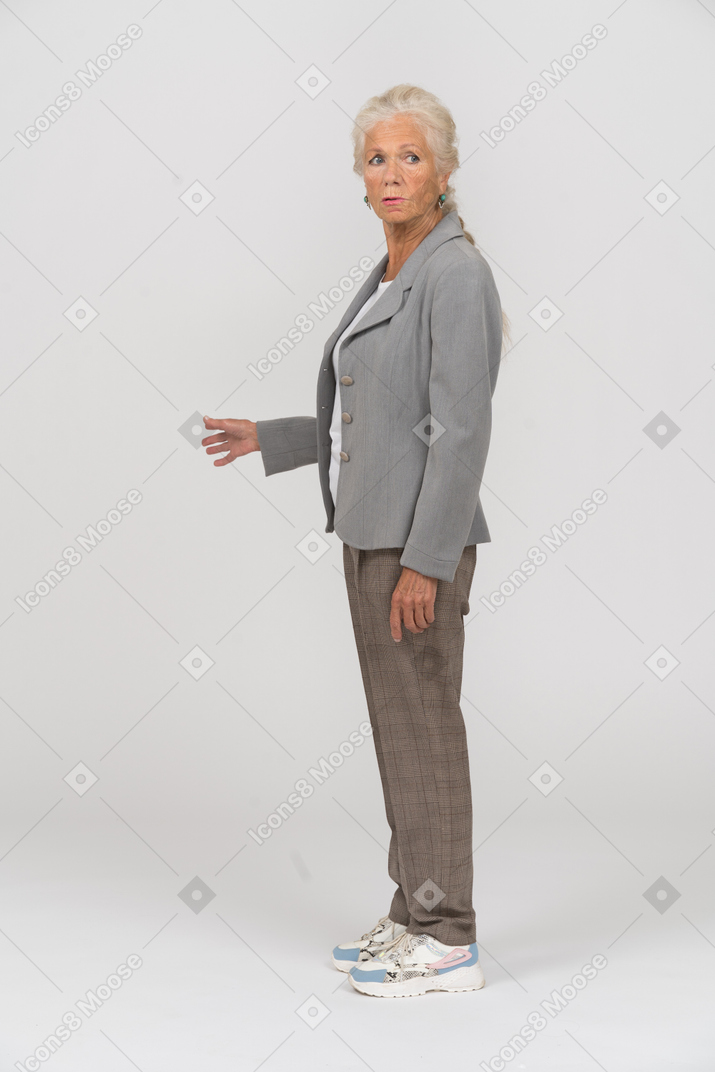 Vista laterale di una vecchia donna in abito che fissa qualcosa