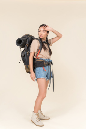 Tired looking young female asian hiker touching her forehead