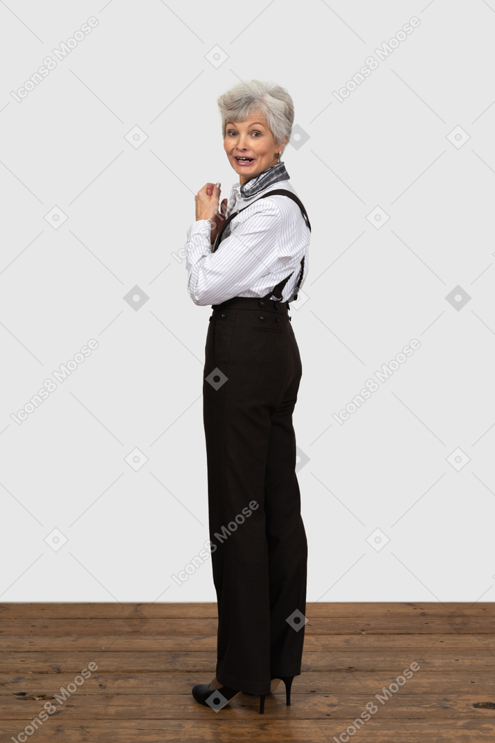 Full-length of an old surprised female in office clothes turning back and talking